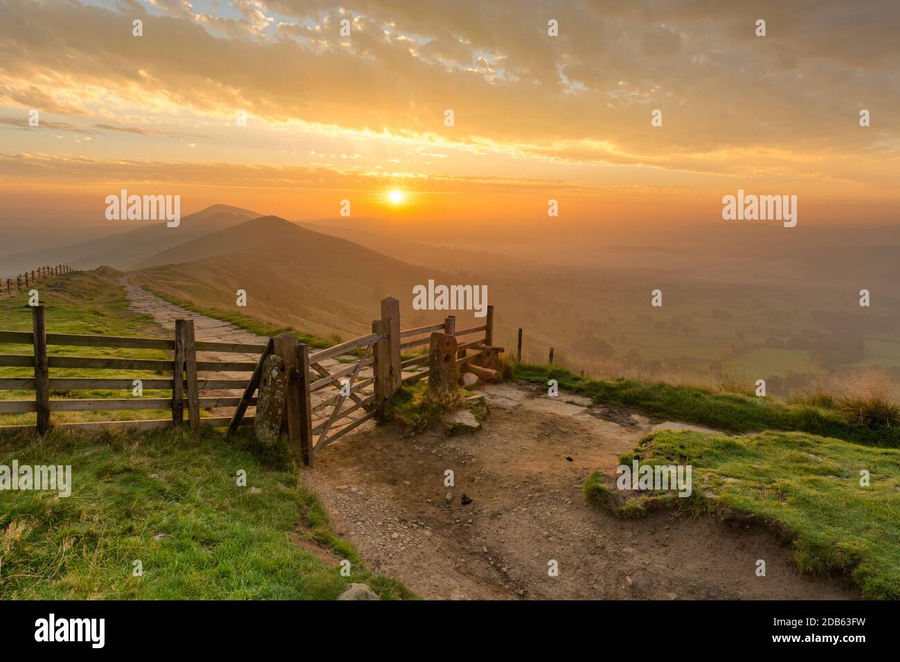 Golden sunrise at Mam Tor in the English Peak District on a hazy Autumn Morning with wooden gate. Stock Photo