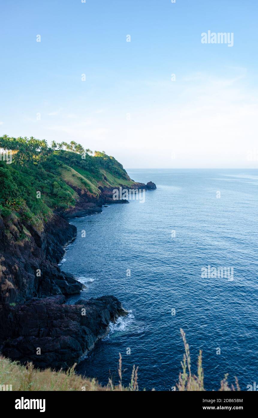 Beautiful view of Arabian sea meeting rocky shoreline and coconut palm trees from inside Cabo de Rama Fort, Canacona, Goa, India Stock Photo