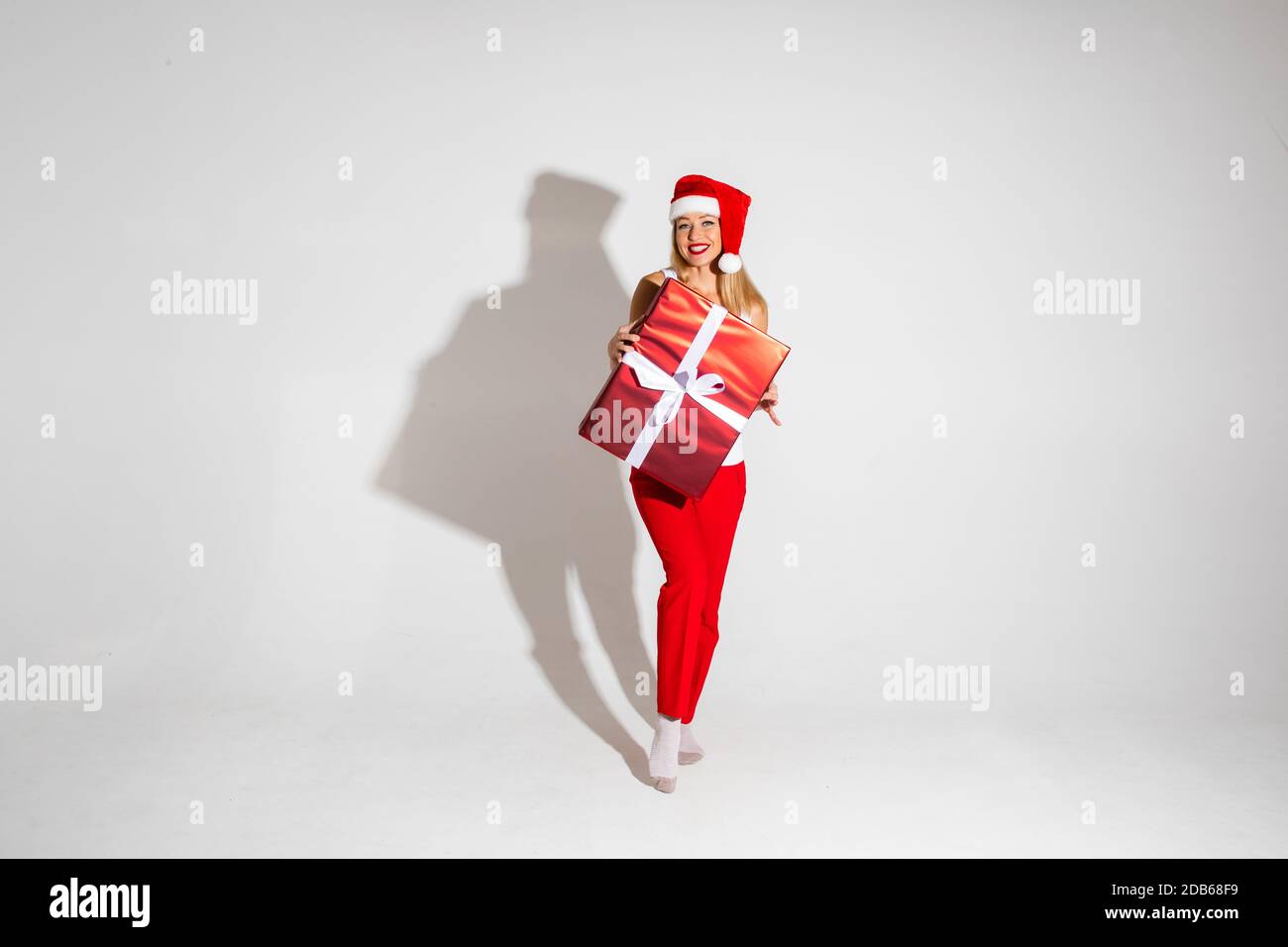 Pretty woman with wrapped Christmas present. Christmas gift wrapped in red paper with white bow.. Stock Photo