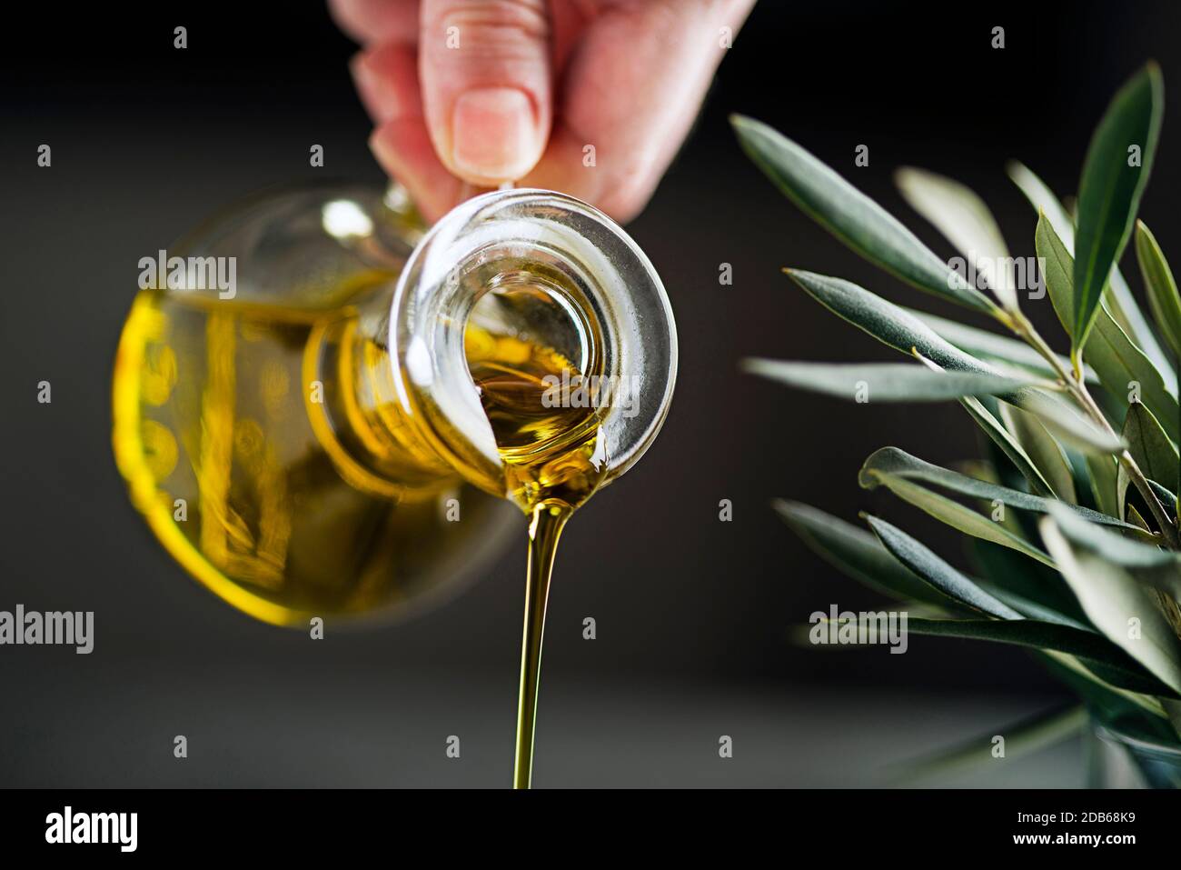 Bottle of Extra virgin olive oil pouring on dark background. Healthy food concept. Stock Photo