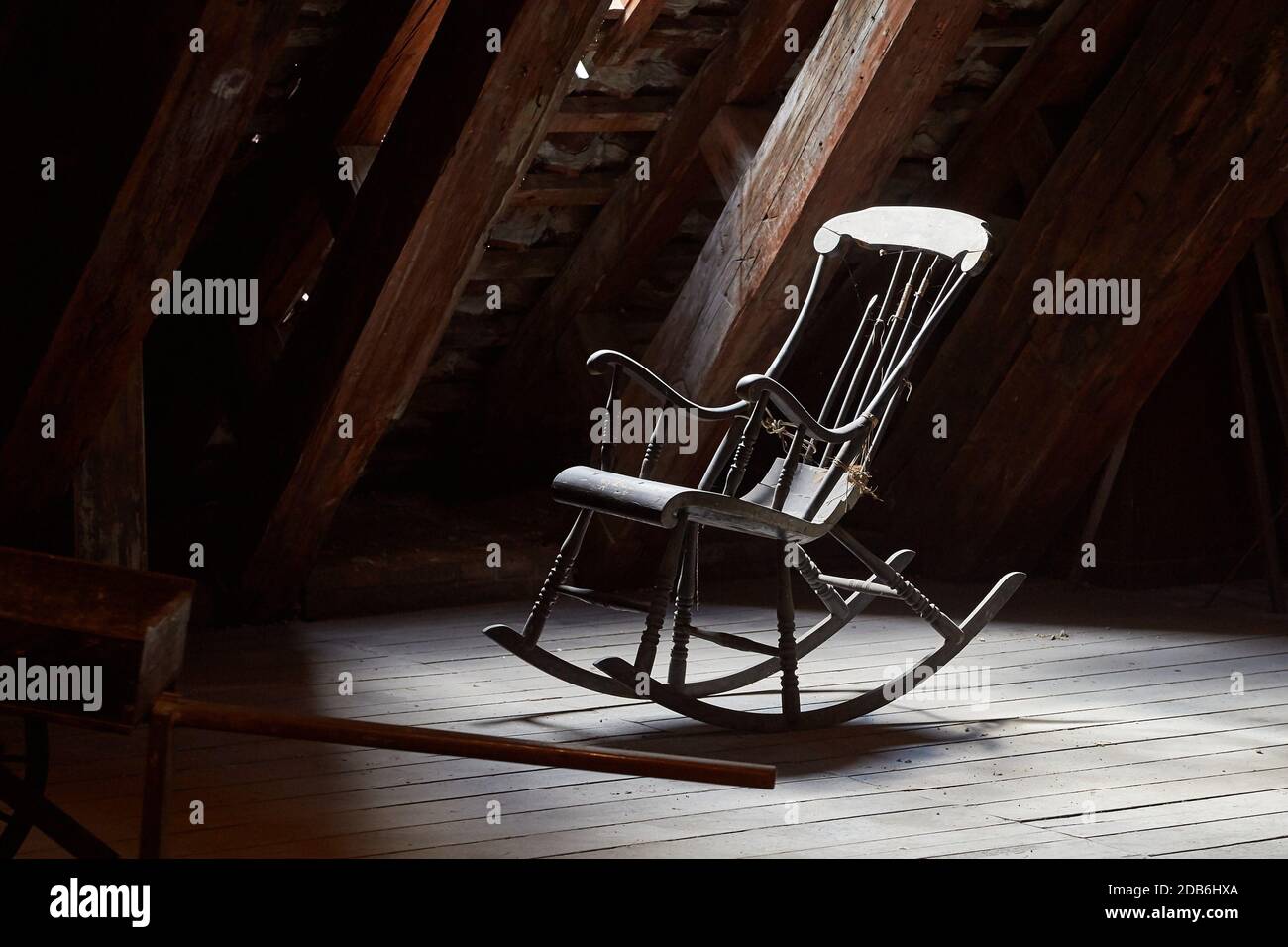 Old rocking chair on a dim attic window light Stock Photo