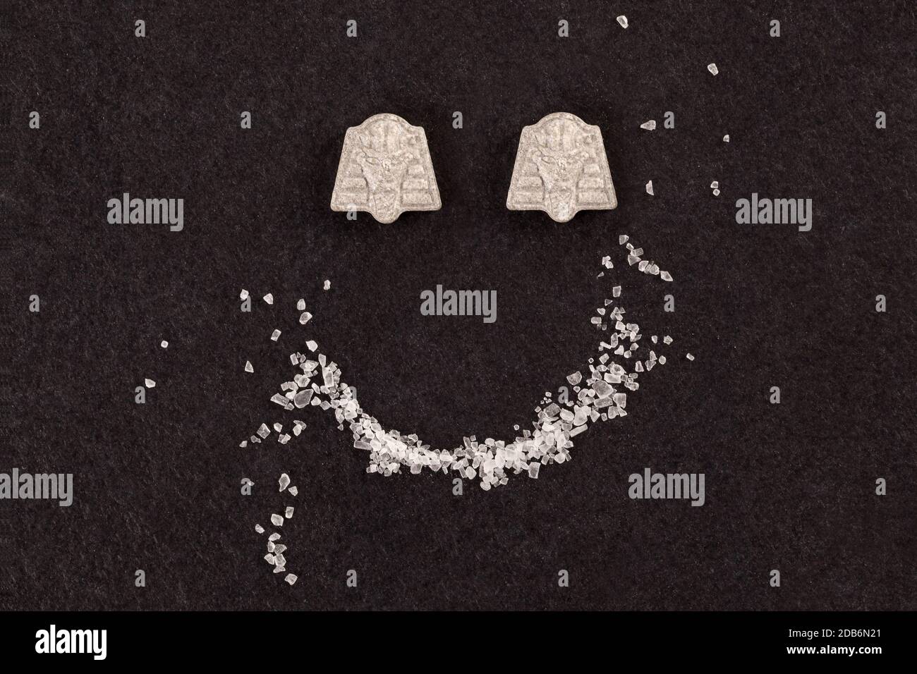 MDMA crystal and ecstasy pills forming smiley face. Stock Photo