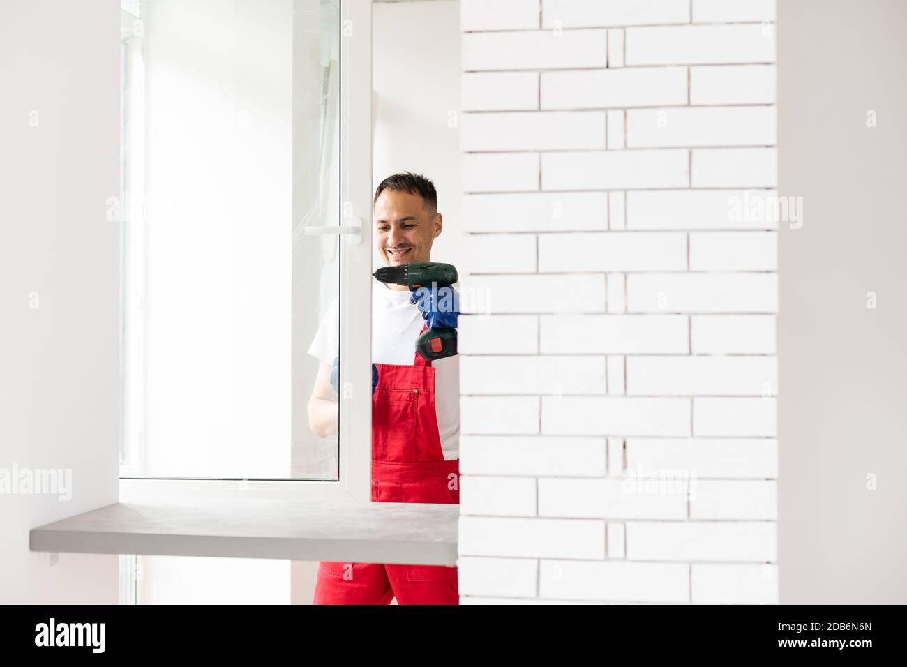 master with a screwdriver sets fittings on the window Stock Photo