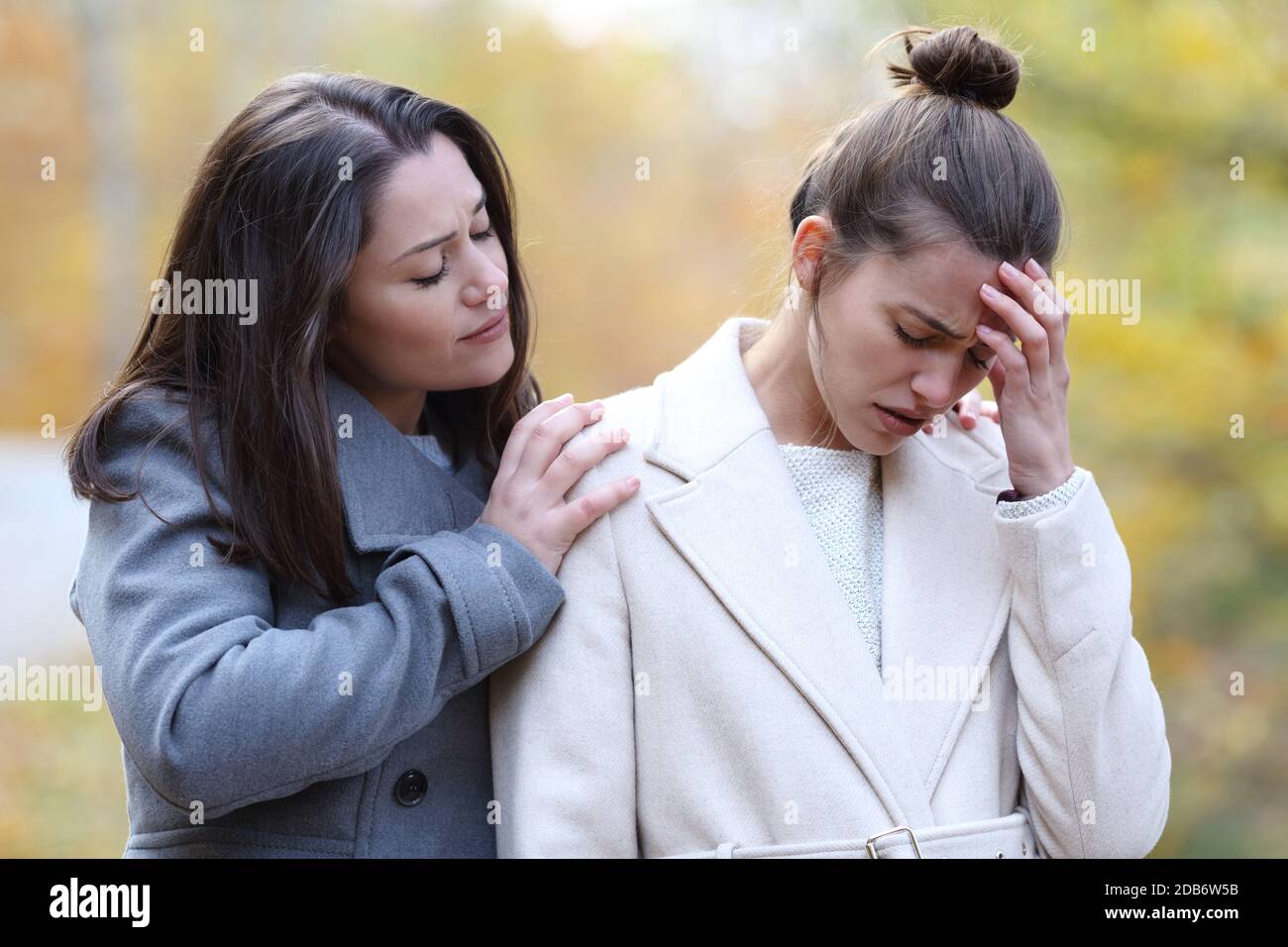 Woman comforting her sad best friend who is complaining in a park in winter Stock Photo