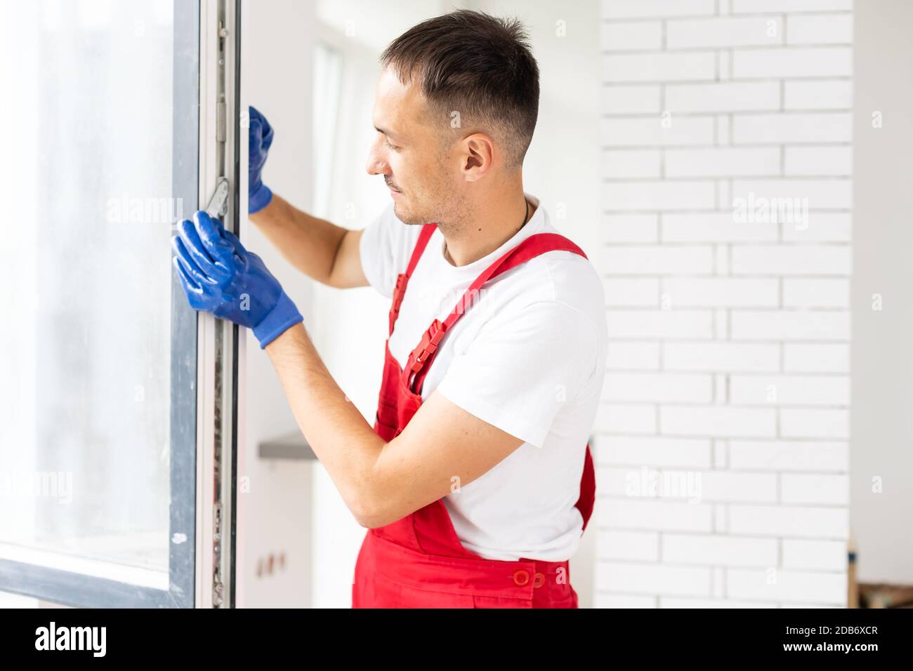 master with a screwdriver sets fittings on the window Stock Photo