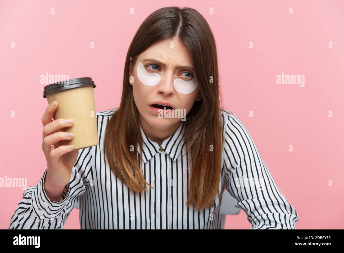 Exhausted tired woman with brown hair in striped shirt drinking coffee ...