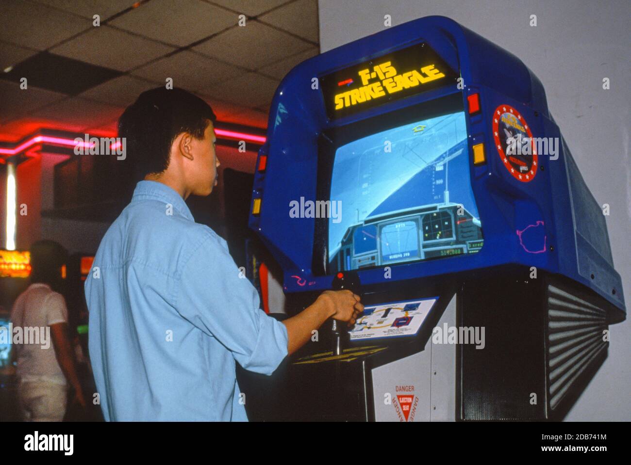 BOSTON, MASSACHUSETTS, USA, NOVEMBER 1990:  Arcade computer video game F-15 Strike Eagle played by man in arcade. Video game simulates air warfare. Stock Photo