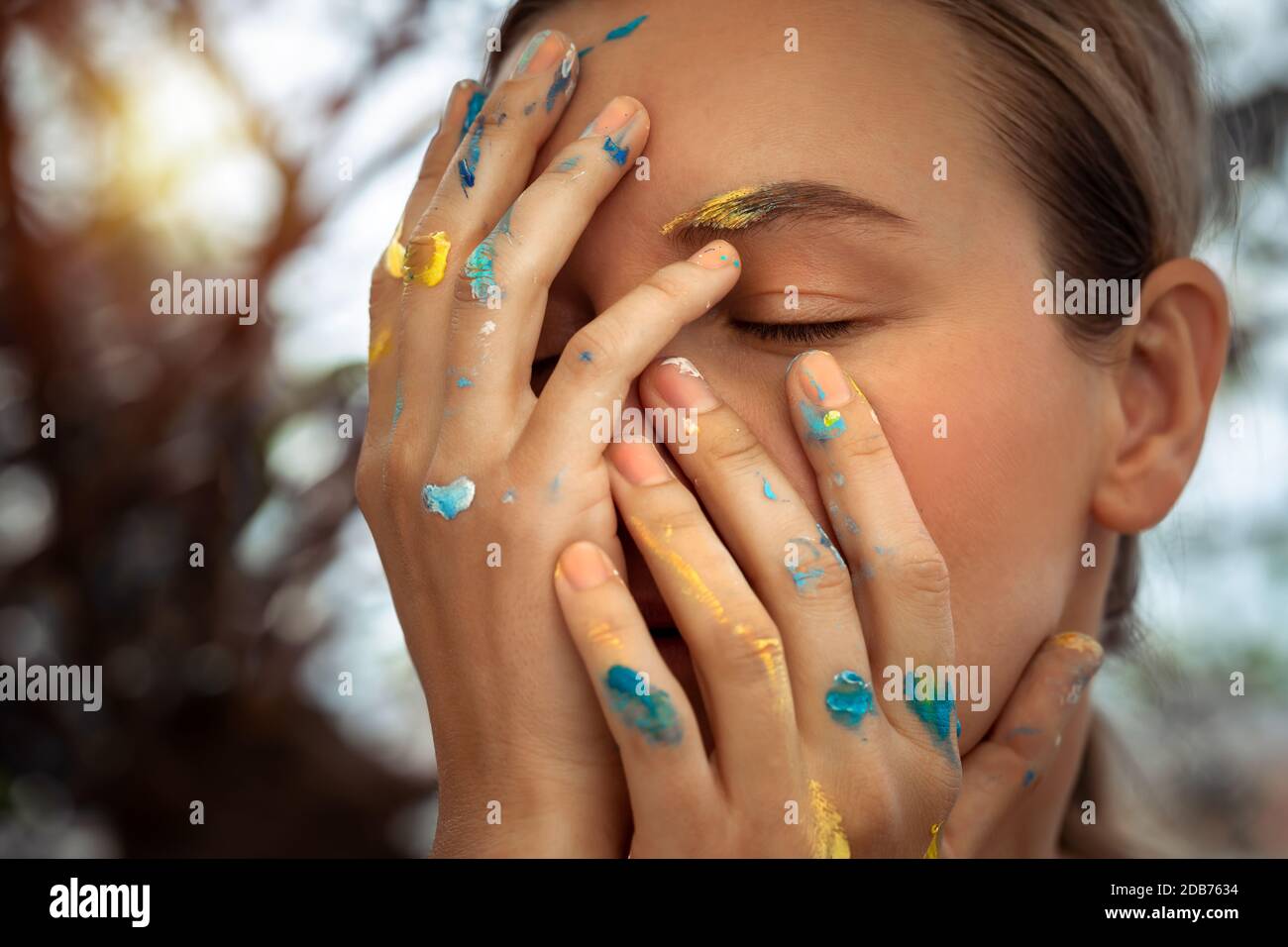 Closeup photo of a dreamy girl with closed eyes and stained hands in paint, modern artist, conceptual photo of a generation with a new ideas Stock Photo