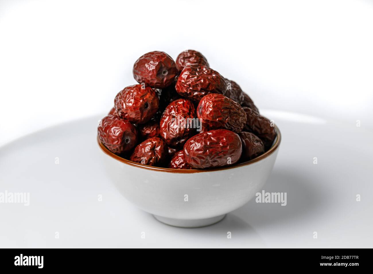 Dried Chinese dates in a ceramic cup on a white background Stock Photo