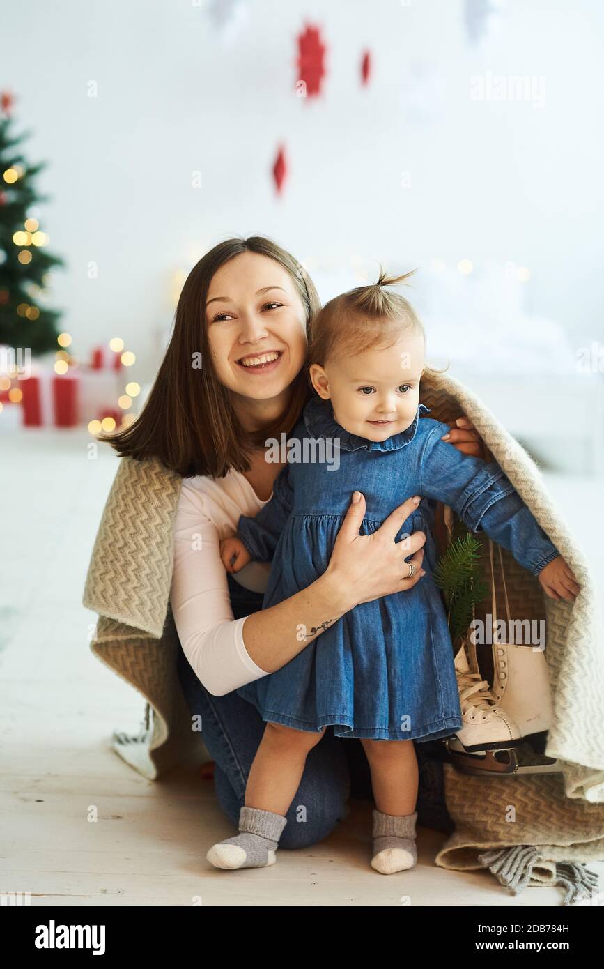Christmas background. Portrait of happy mother and her daughter having fun and covered with blanket. Stock Photo