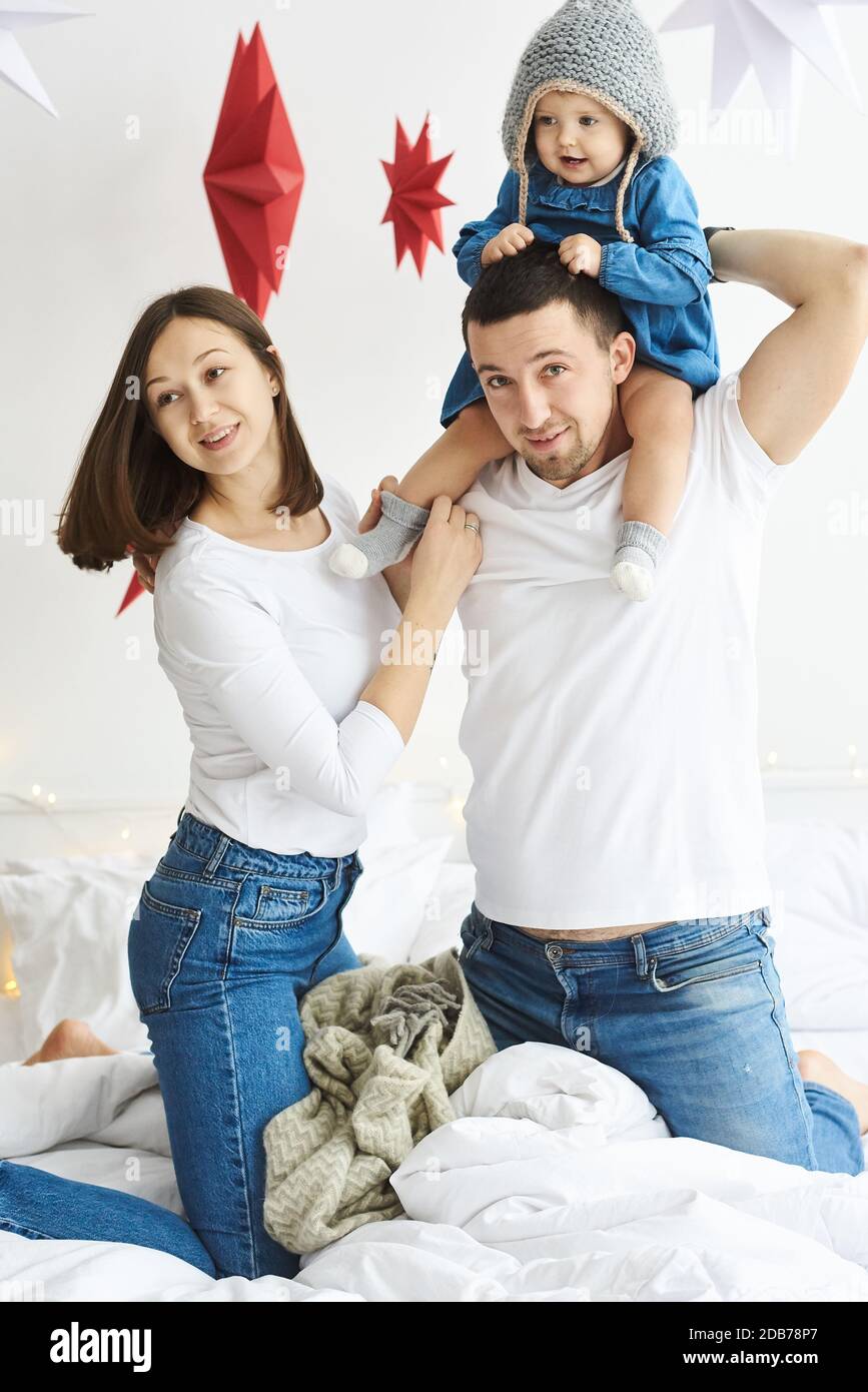 Happy mom dad and daughter playing on the bed in the bedroom on Christmas morning. Stock Photo