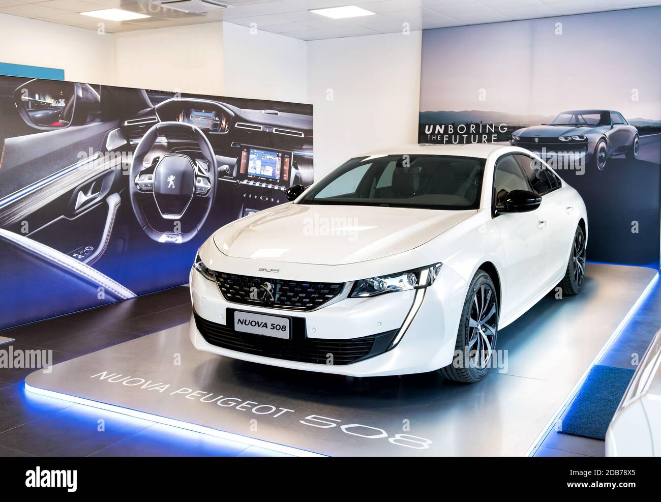 New white Peugeot 508 displayed in a dealership or motor show under overhead lighting on a raised platform in a showroom Stock Photo