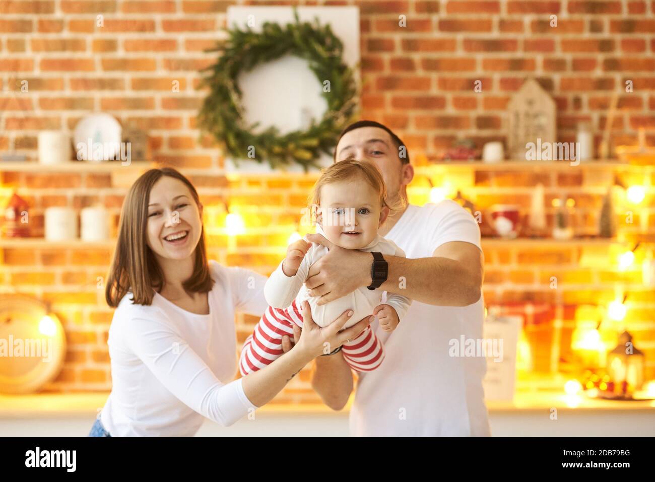 Young family with a small child having fun at Christmas at home in a cozy bright room. Stock Photo