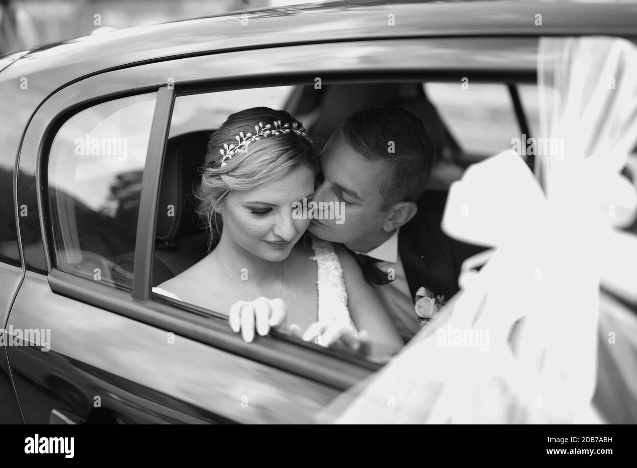 Black and white photo of wedding couple in car. Wife and husband enjoy moment of happiness. Portrait of happy newly wed couple in car Stock Photo