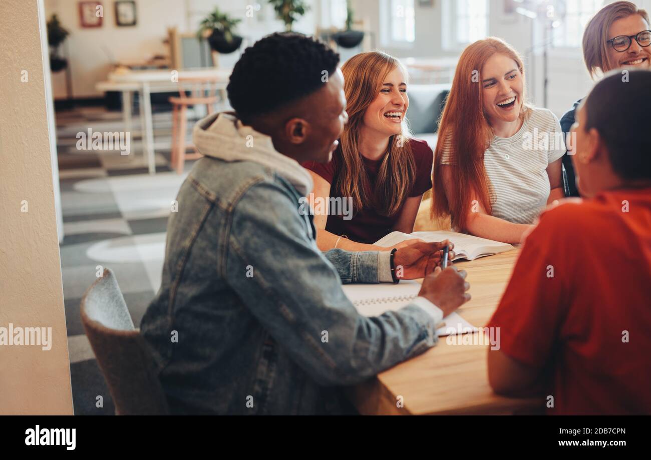 Group of multi-ethnic students in classroom. Study group sitting at table and smiling in university. Stock Photo