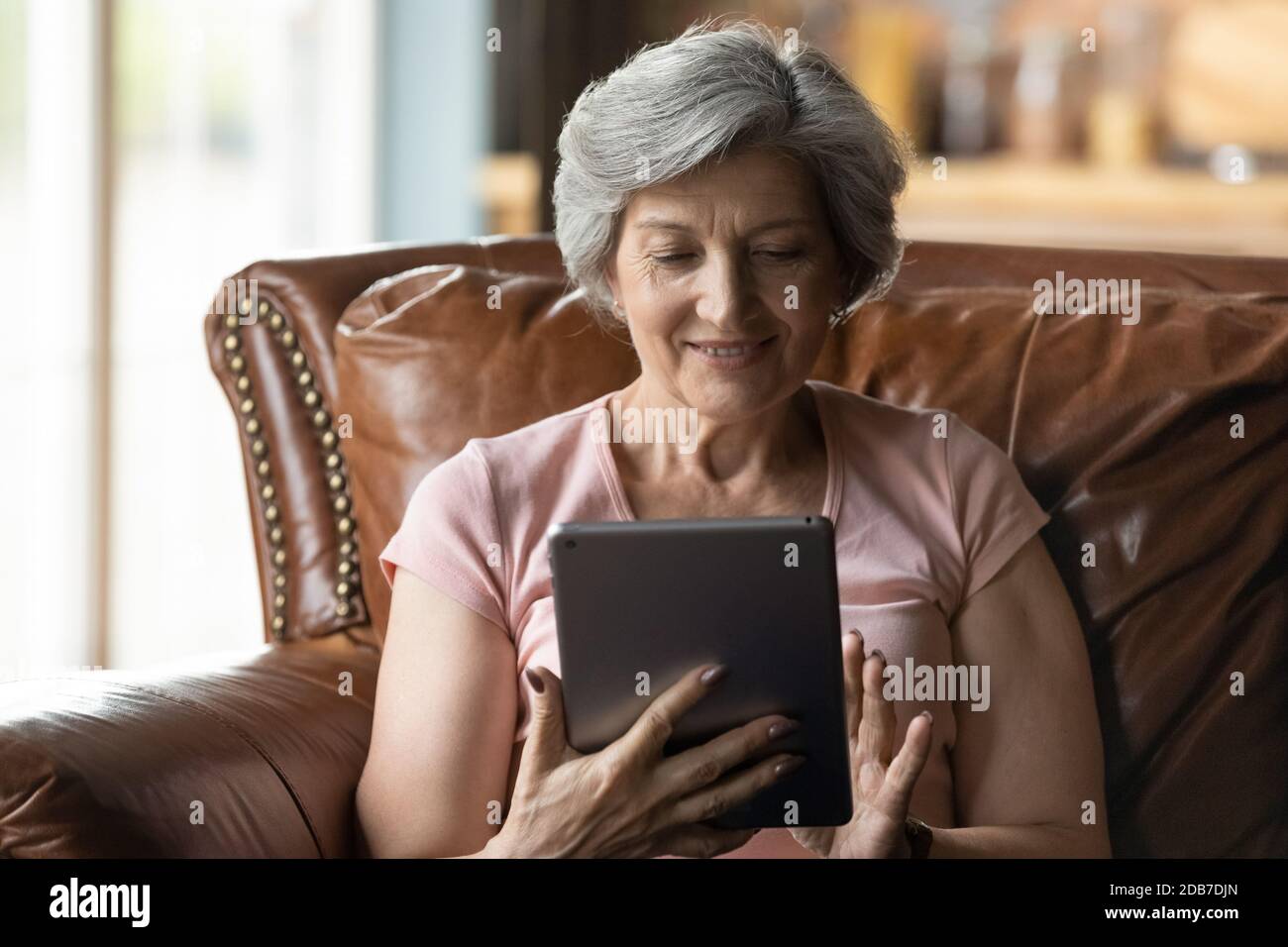 Close up smiling mature woman using tablet, having fun online Stock Photo