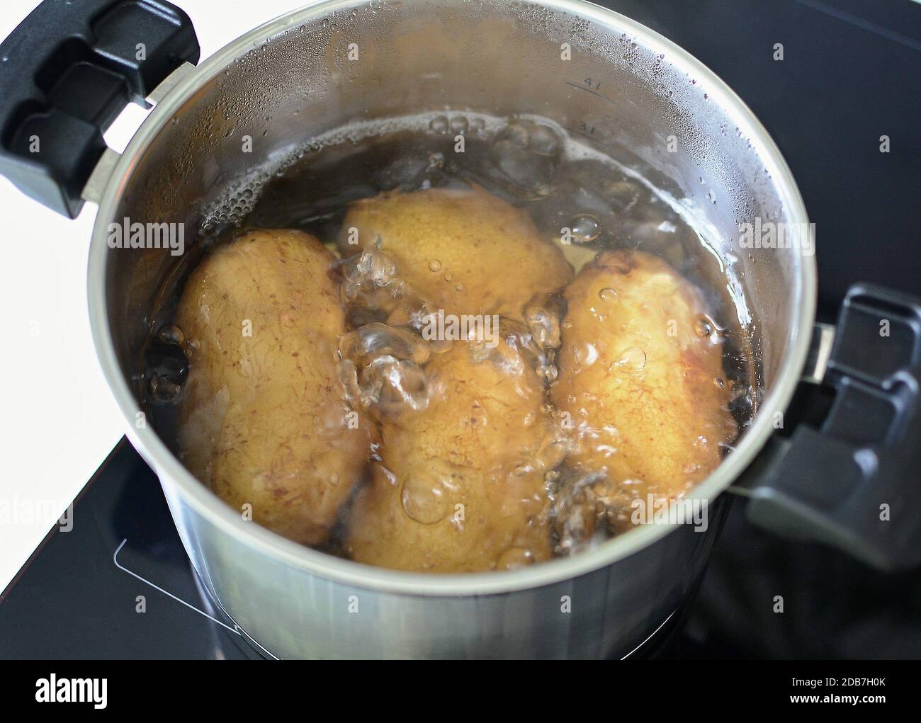 Top view of boiling whole potatoes in hot water in silver saucepan