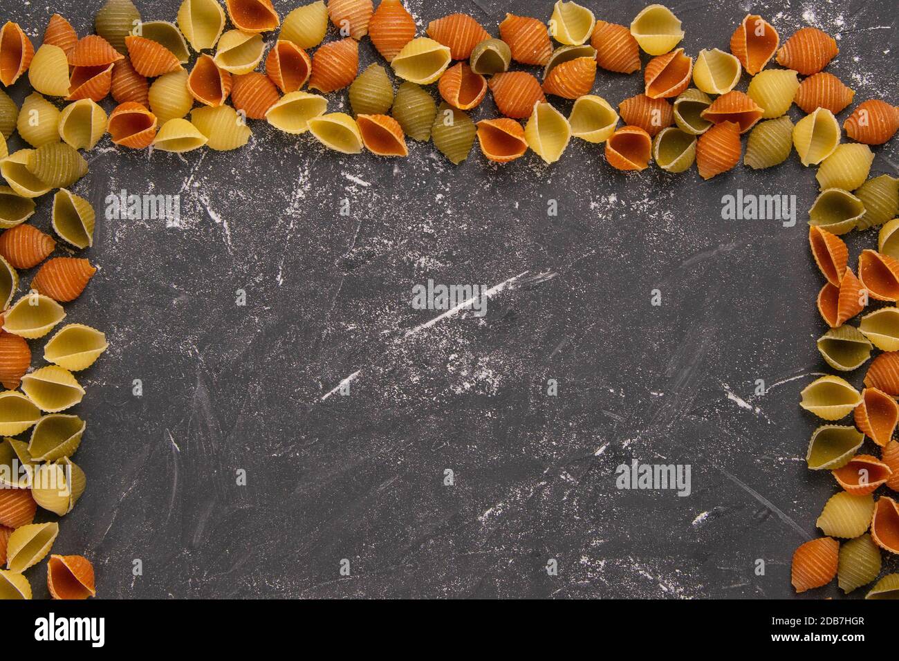 Pasta Conchiglie Rigate, mix of colorful uncooked shells in the shape of a rectangle with an empty middle. Textured Italian food background concept. T Stock Photo