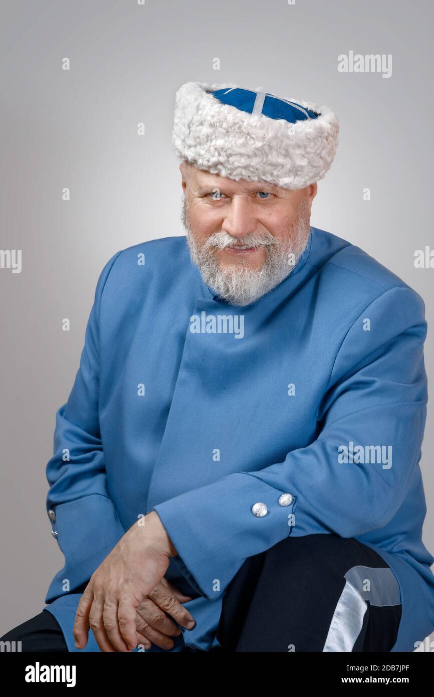 elderly man with a gray beard in a hat and a blue caftan. Cossack costume Stock Photo