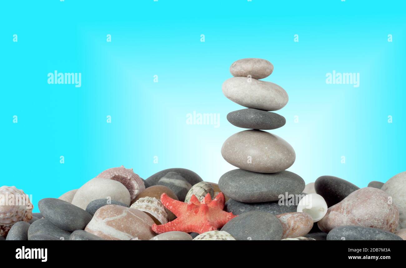 The pyramid of stones with sea shells on a blue background Stock Photo ...