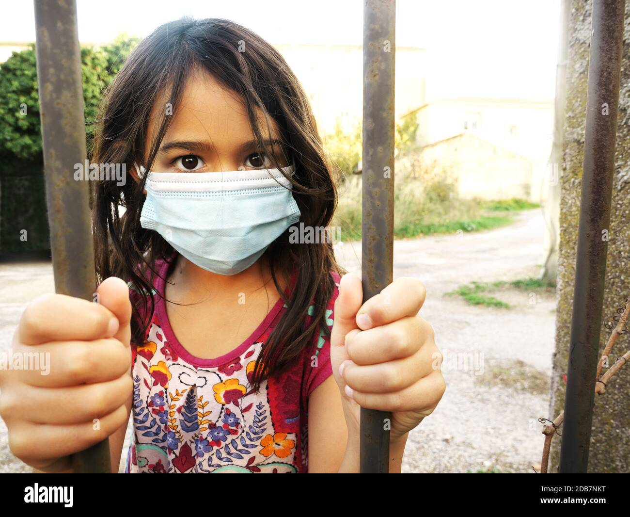 Photo of a little girl wearing a mask and holding bars Stock Photo
