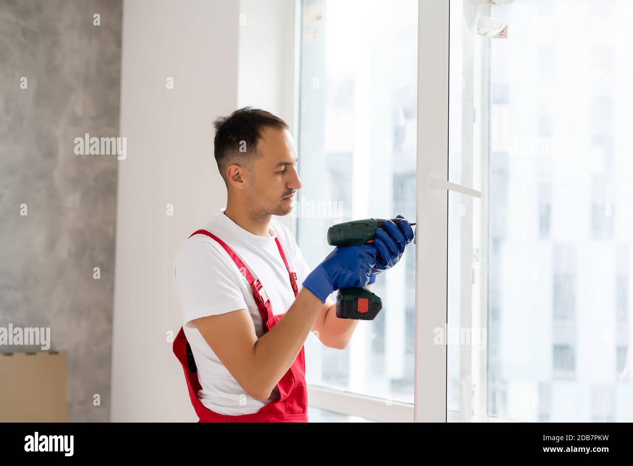 master with a screwdriver sets fittings on the window Stock Photo