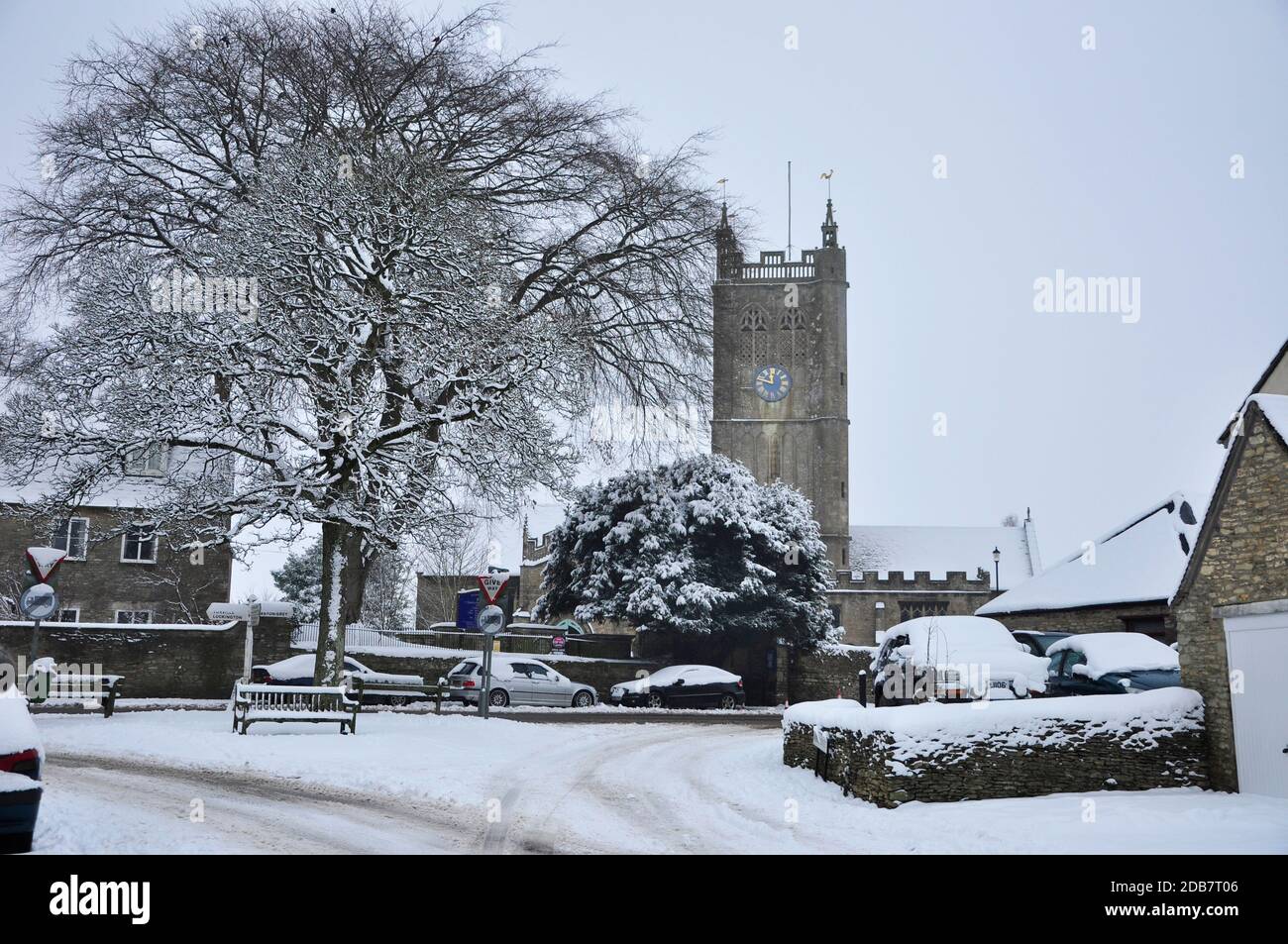 A snowy scene at Sherston in Wiltshire. The Church of the Holy Cross with vehicles and trees covered in snow.UK Stock Photo