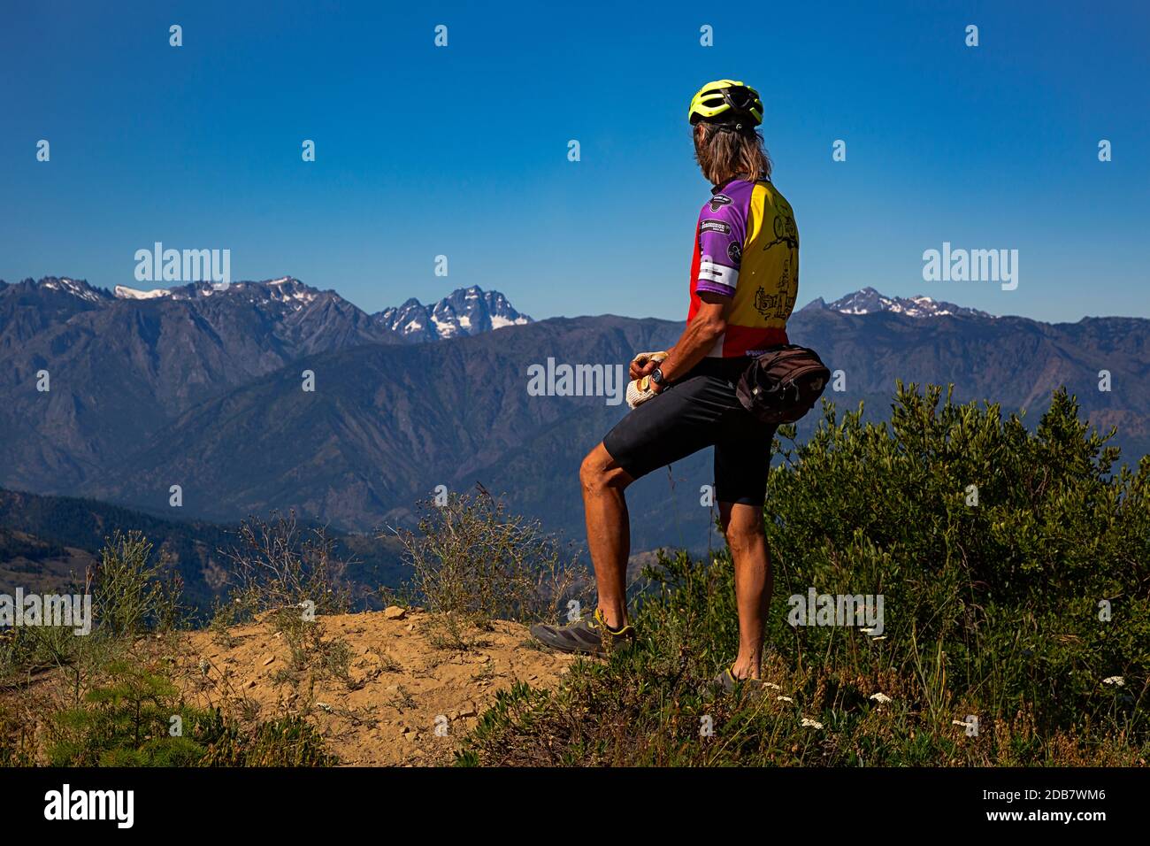 WA18137-00...WASHINGTON - Cyclist checking out the view from turnout along the Chumshick Mountain Road with Mount Stuart and Little Annapurna in view Stock Photo