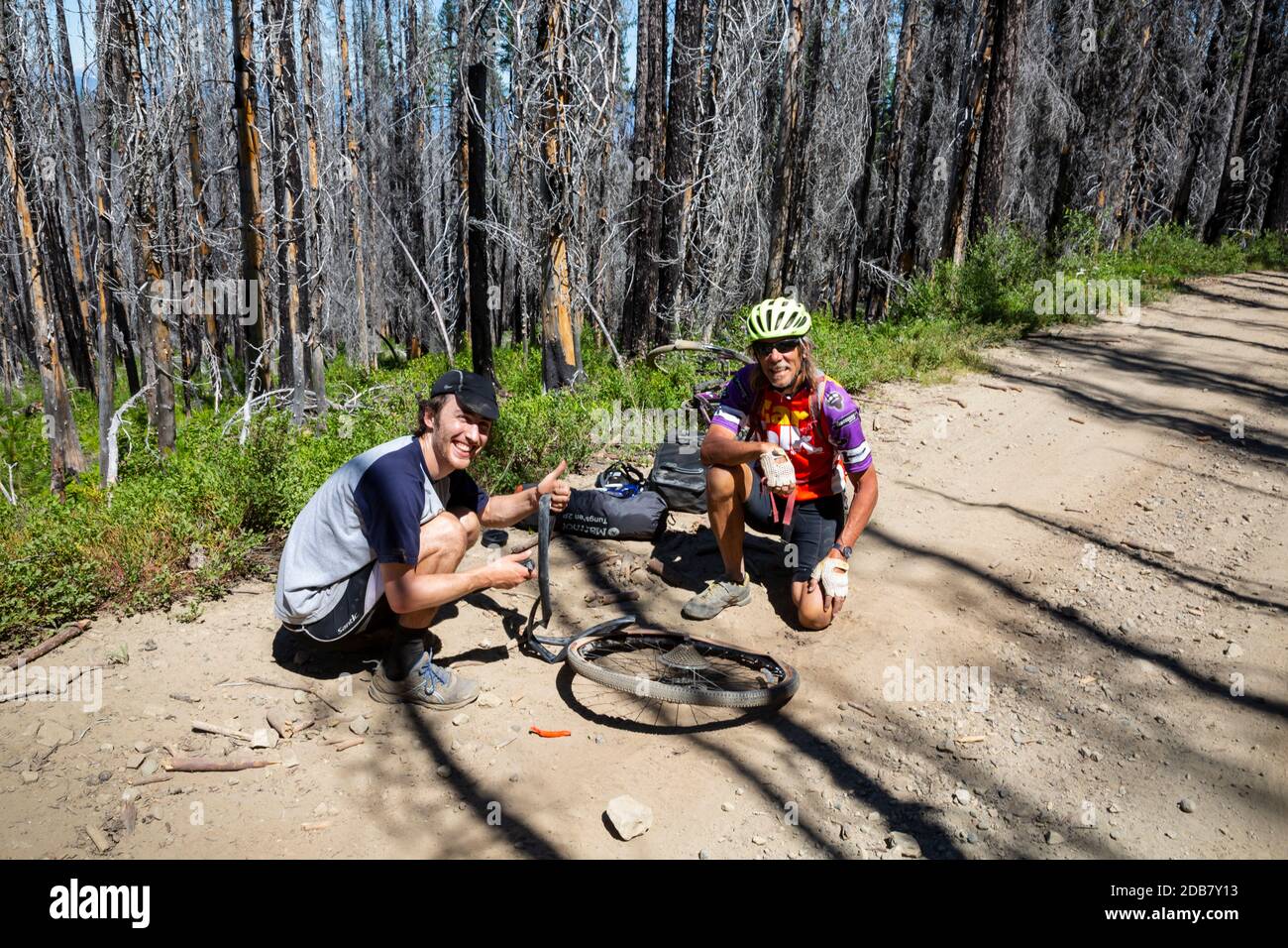 WA18144-00...WASHINGTON - Tom helping and instructing a weekend rider on how to fix a flat tire on Road 9712 across Table Mountain in the Wenatchee NF Stock Photo