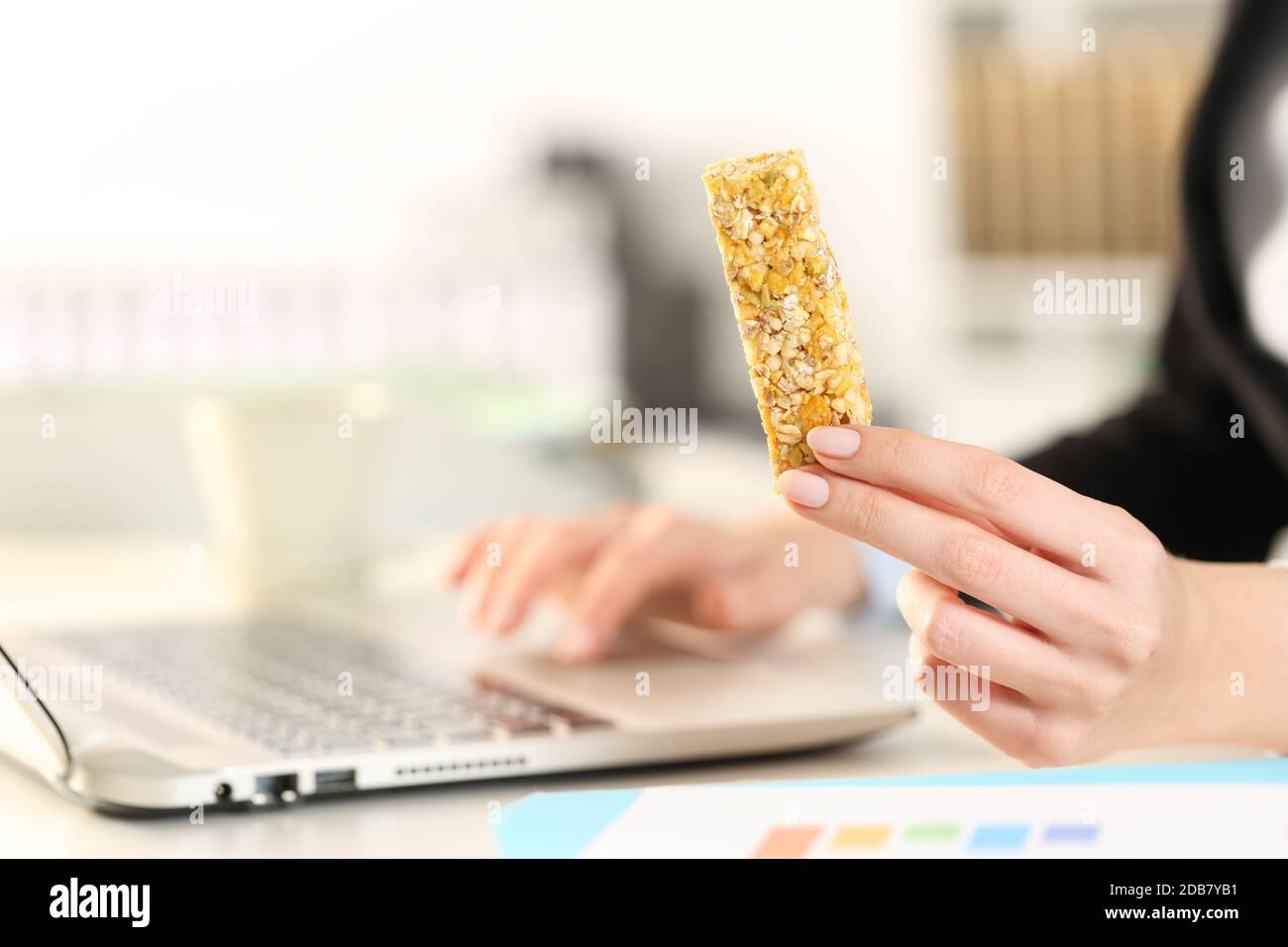 Close up of business woman hands with laptop holding snack bar on a ...