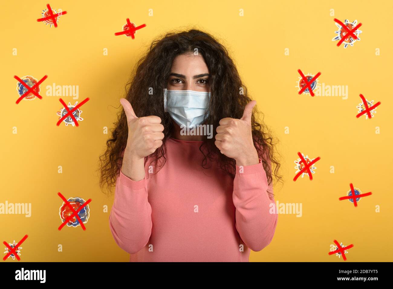Girl is optimistic about the defeat of covid 19 coronavirus. yellow background. Stock Photo