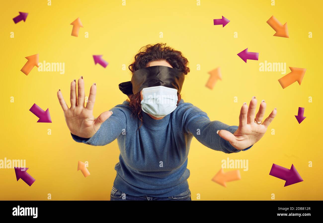 Woman with mask and blindfold has difficulty to find the right way. concept of uncertainty. yellow background Stock Photo