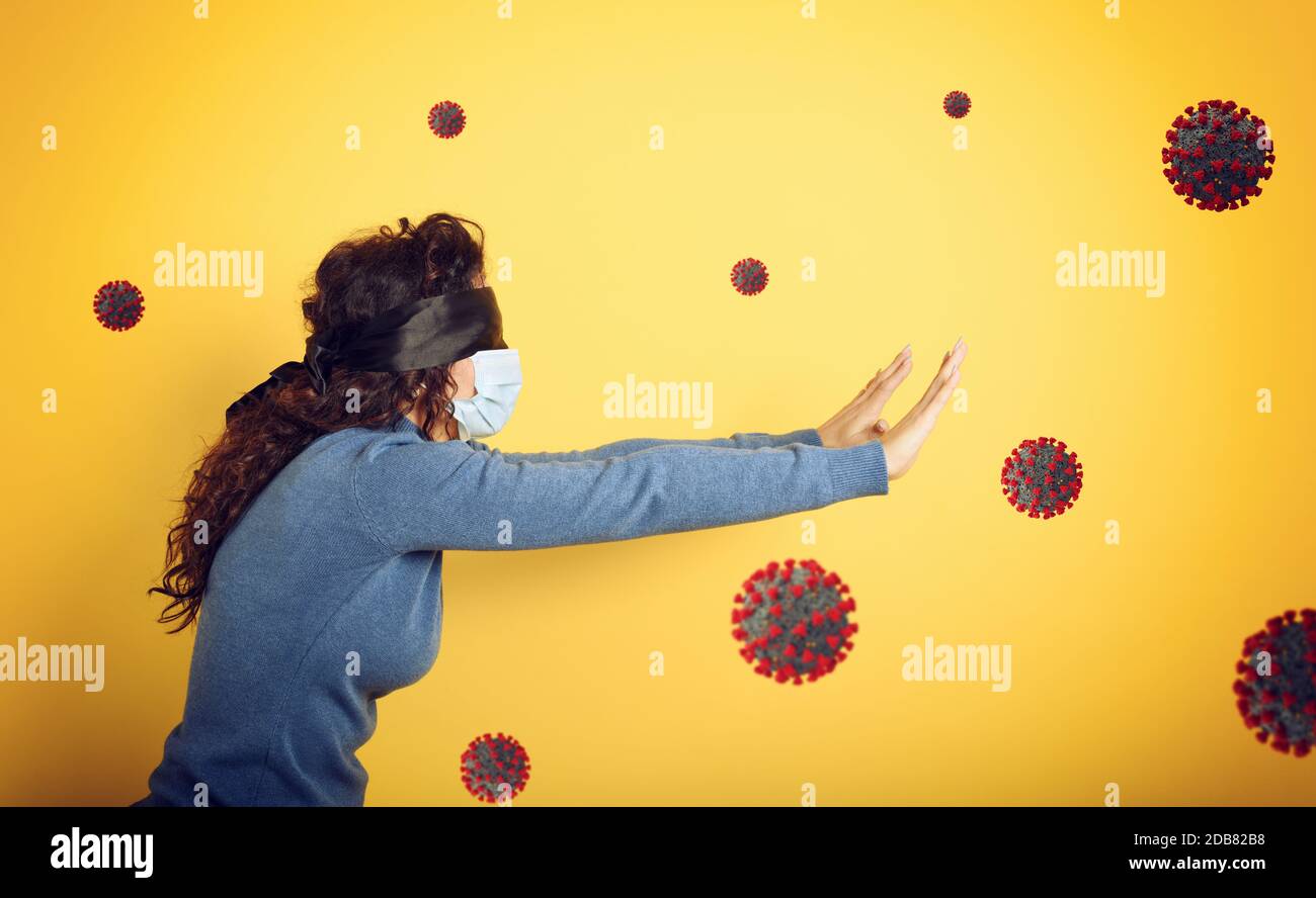Woman with mask and blindfold. concept of uncertainty. yellow background Stock Photo