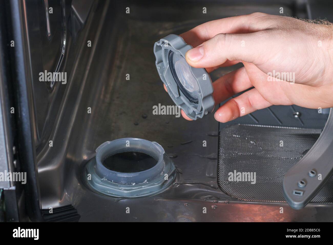 Man opens the container for salt in the dishwasher and fills there a