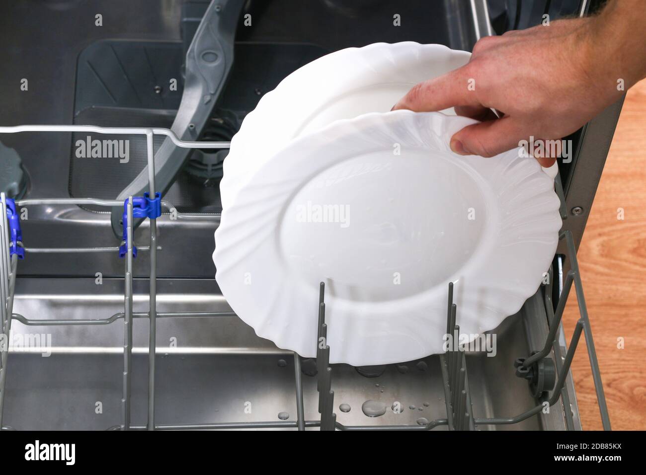 A man loads dirty dishes, plates, spoons, forks, cutlery into the