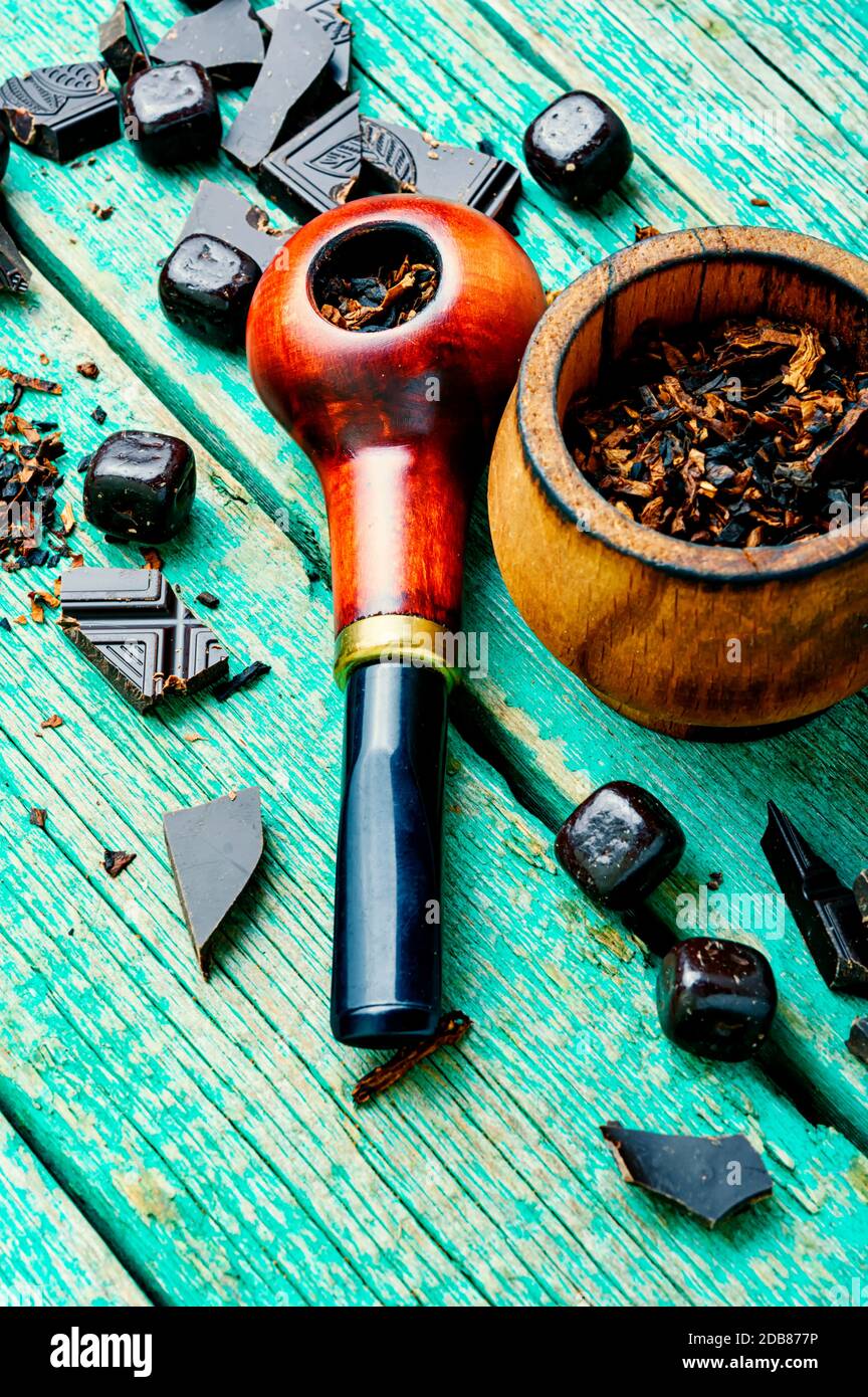 Chocolate flavored tobacco for smoking pipes.Tobacco pipe filled with  tobacco.Smoking pipe on wooden table Stock Photo