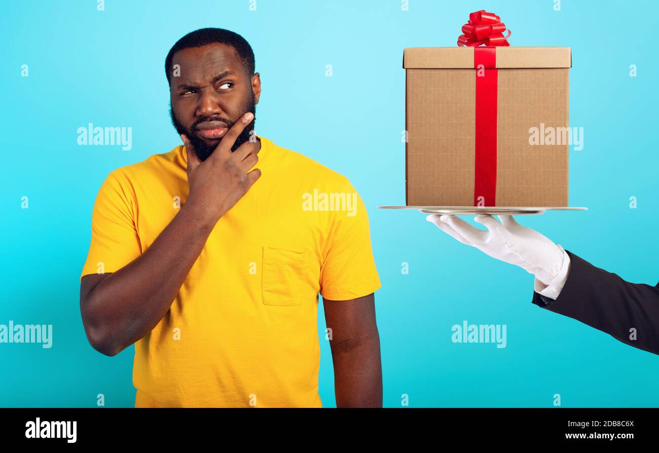 Confused man is suspicious about a gift. concept of options, confusion, indecision Stock Photo
