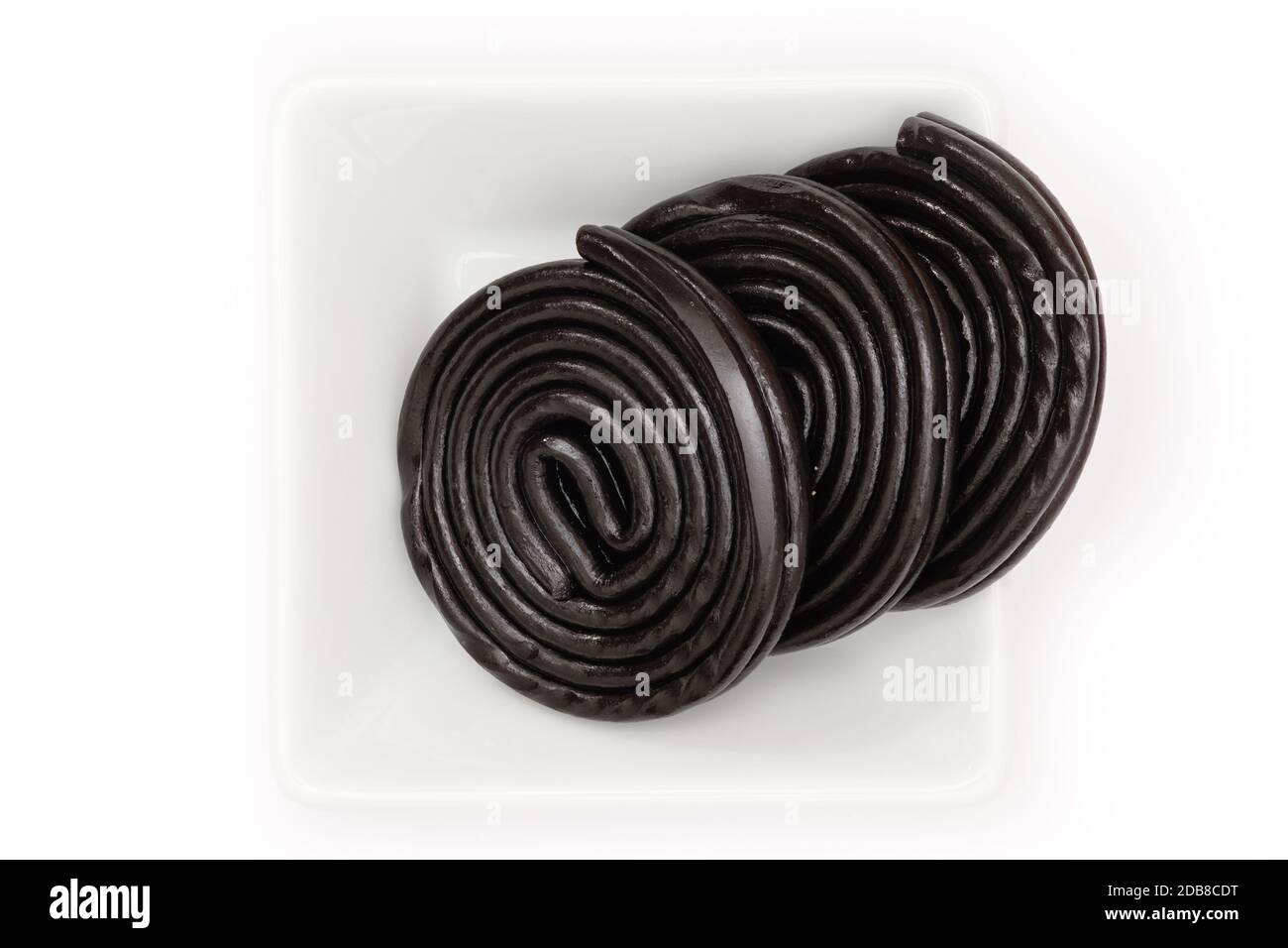 Black licorice wheels in a white bowl in top view Stock Photo Alamy