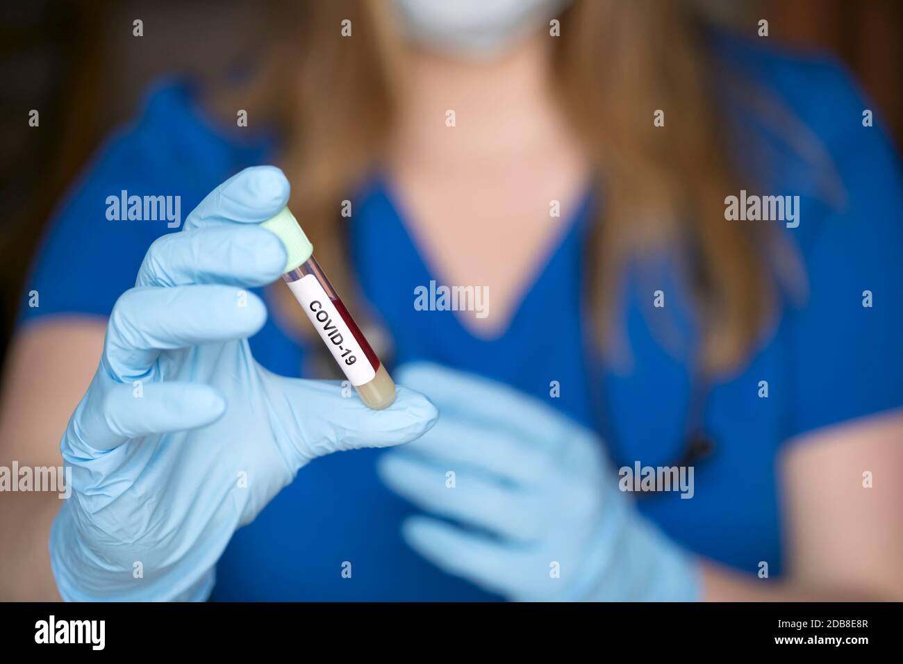 test tube in hand of lab technician with sample of coronavirus covid-19, deadly global pandemic concept Stock Photo