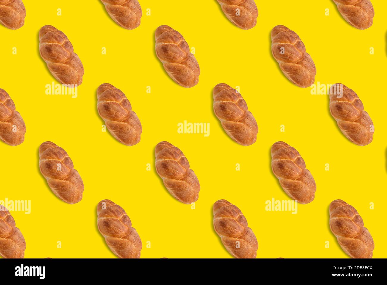 A braided loaf of white bread isolated on a yellow background. Seamless pattern. Original packaging design Stock Photo