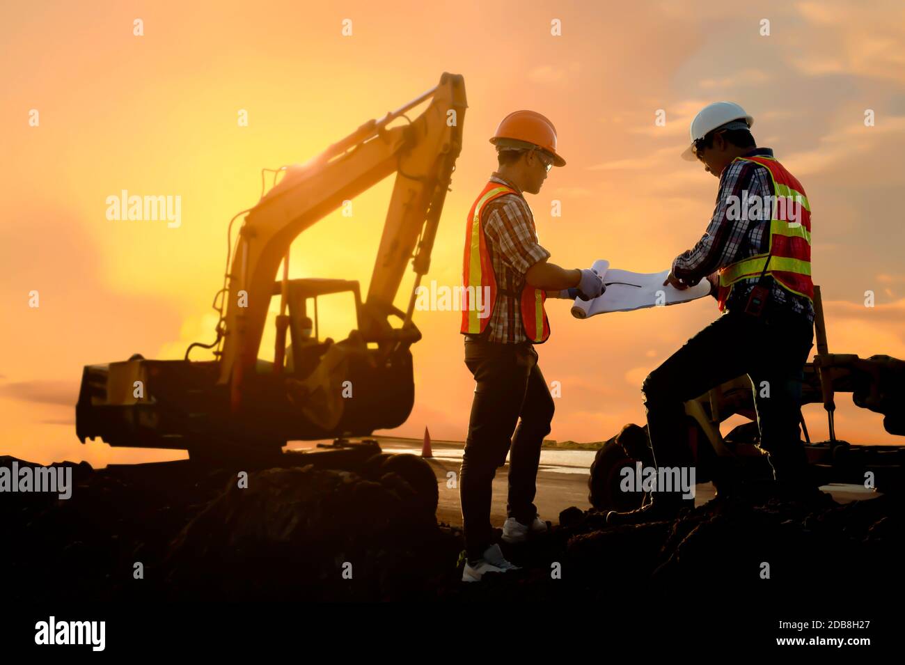 Two engineers looking at building plans on a construction site, Thailand Stock Photo