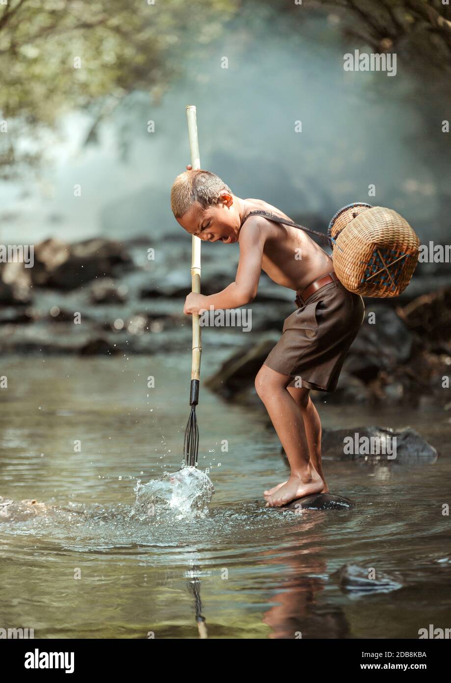 Boy standing on a rock in a river fishing, Thailand Stock Photo