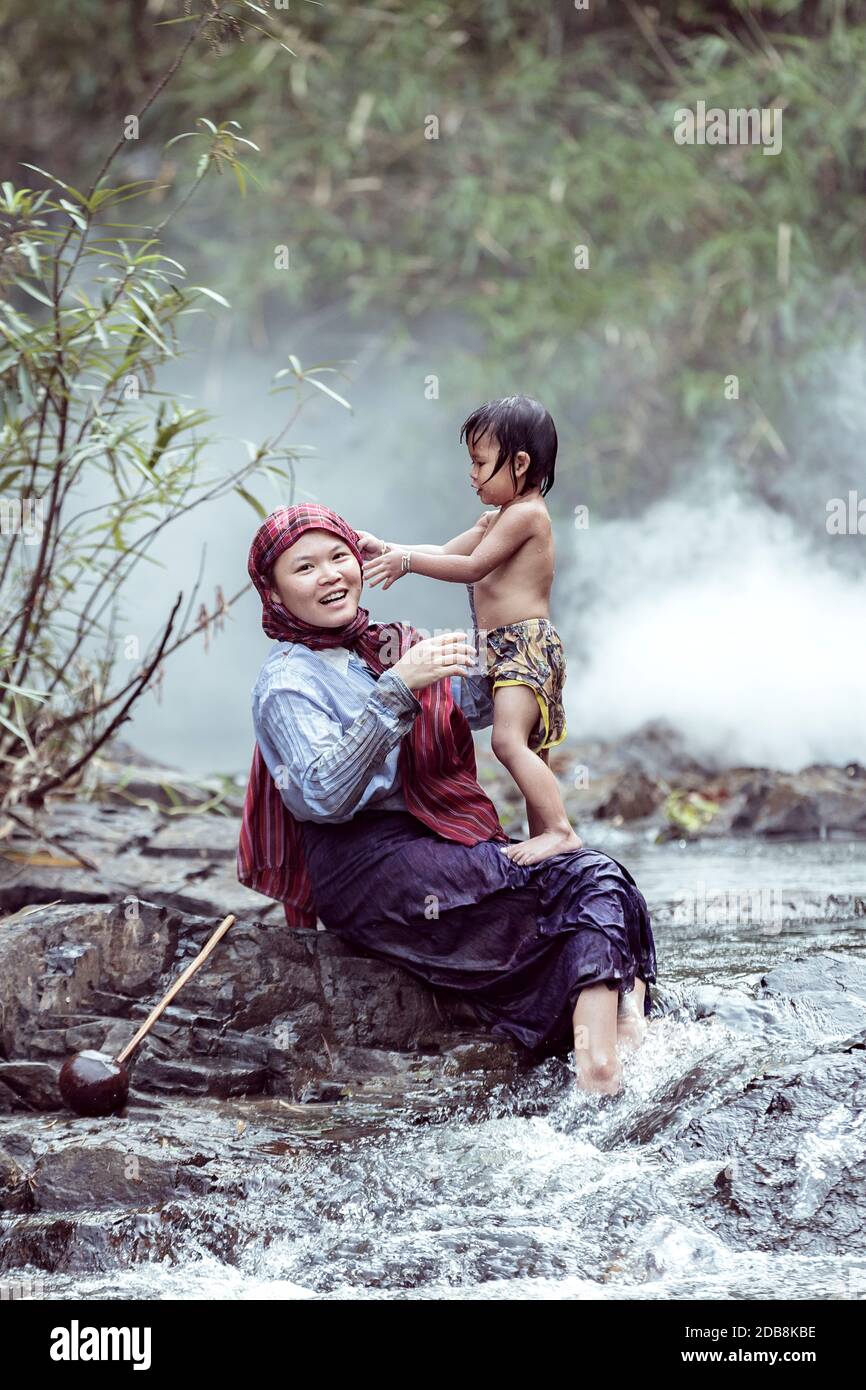 Mother sitting by a river washing her daughter, Thailand Stock Photo