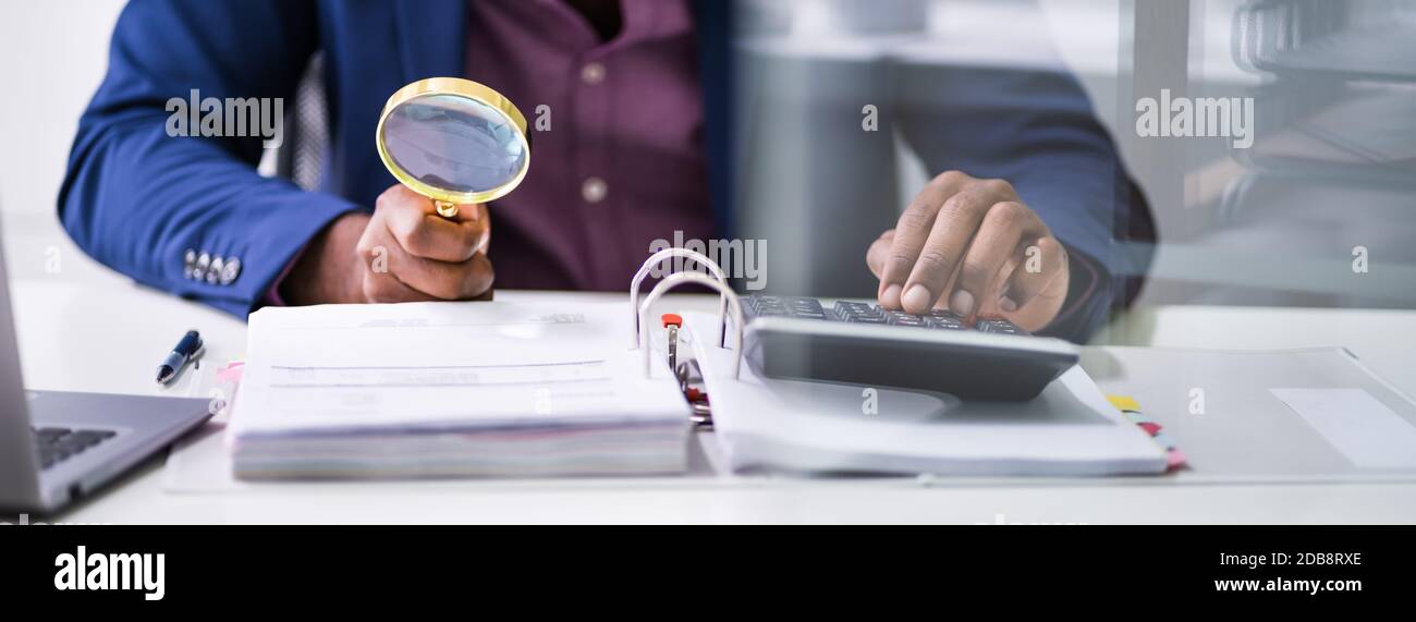 Closeup Of Auditor Scrutinizing Financial Documents At Desk In Office Stock Photo