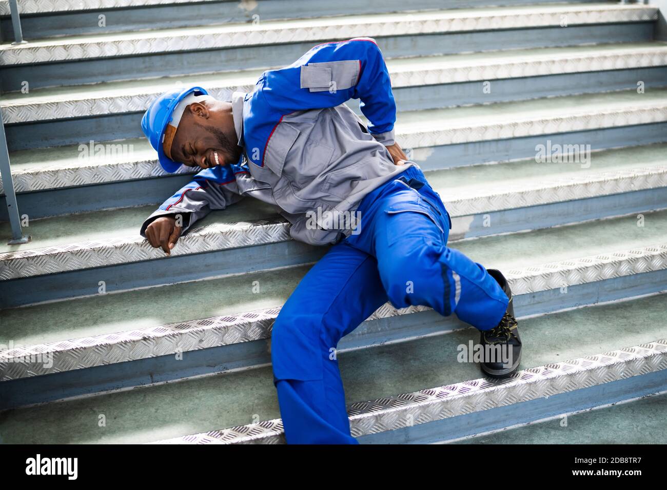 Worker Man Lying On Staircase After Slip And Fall Accident Stock Photo