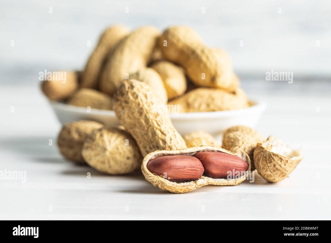 Tasty unpeeled peanuts. Peanuts in nutshell on white table. Stock Photo