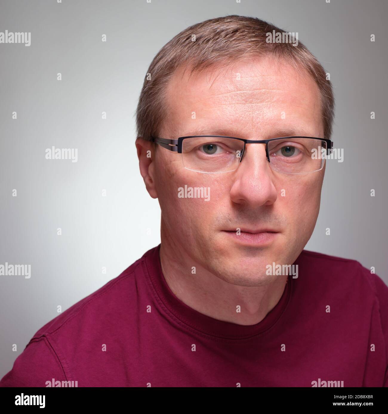 Potrait of a man with glasses and sceptical glimpse grey background Stock Photo