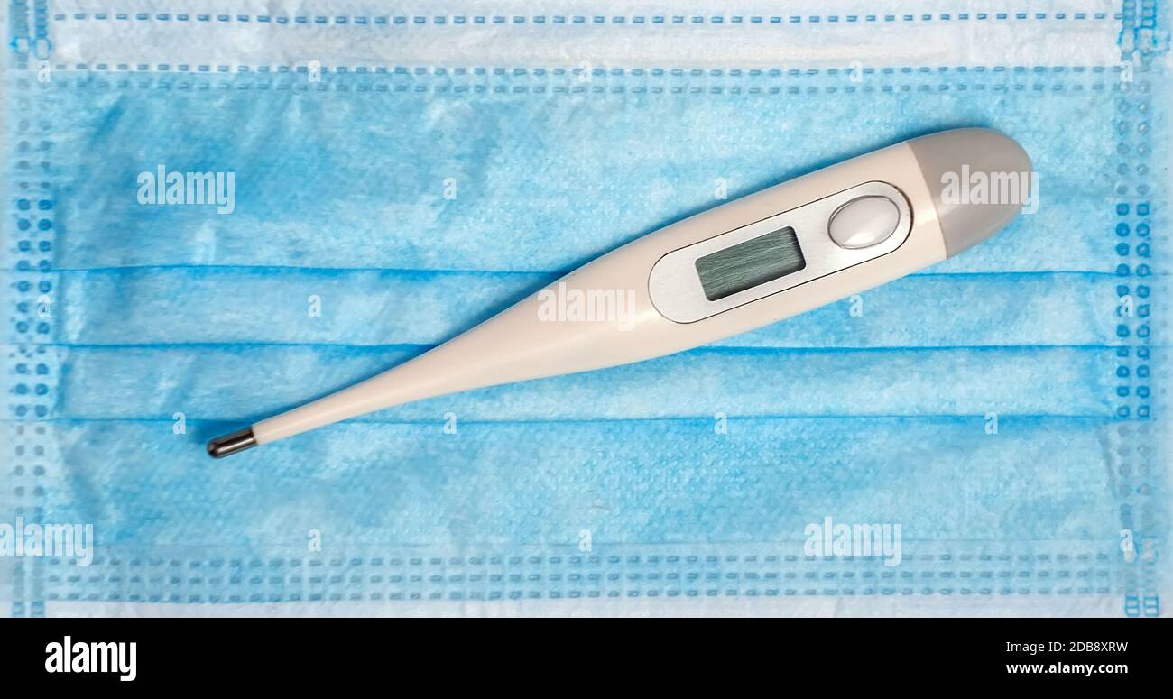 Digital Medical Thermometer Hygienic Waterproof with Fever Indicator in surgical masks background Stock Photo