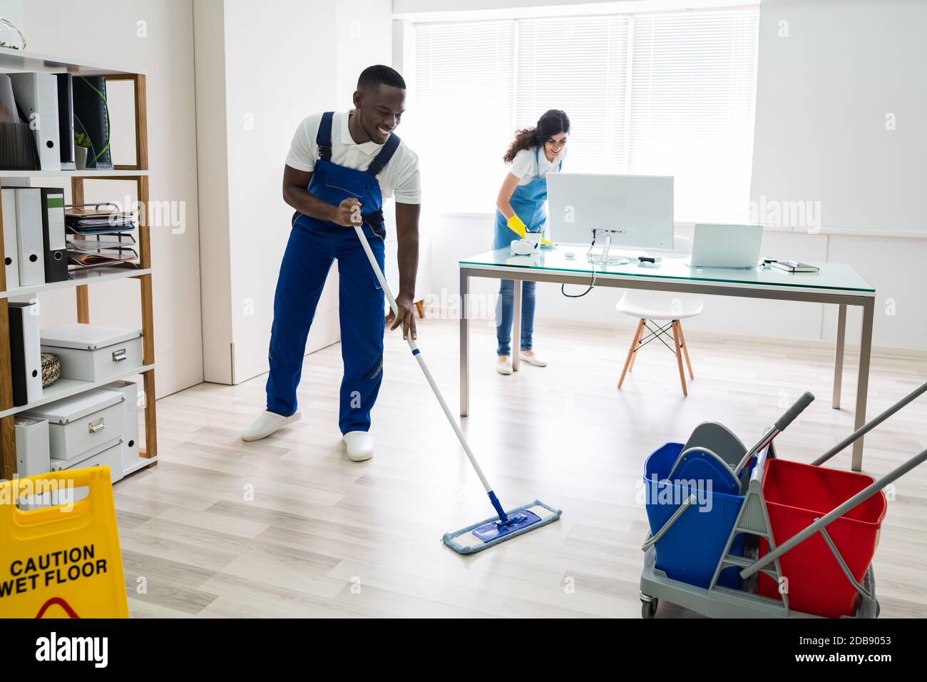 Young Male And Female Cleaners Cleaning Office Stock Photo