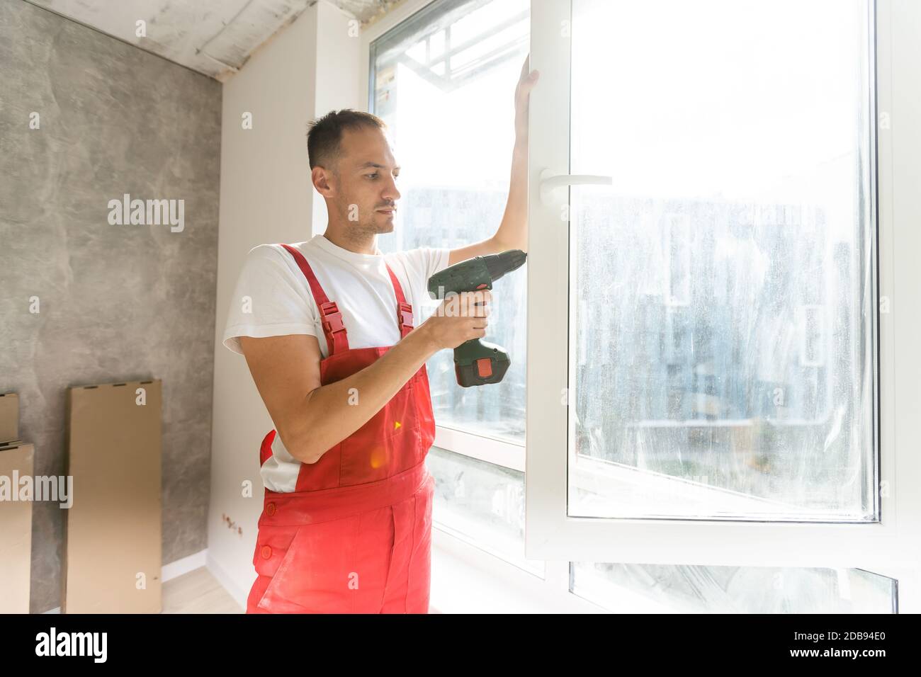 master with a screwdriver sets fittings on the window Stock Photo